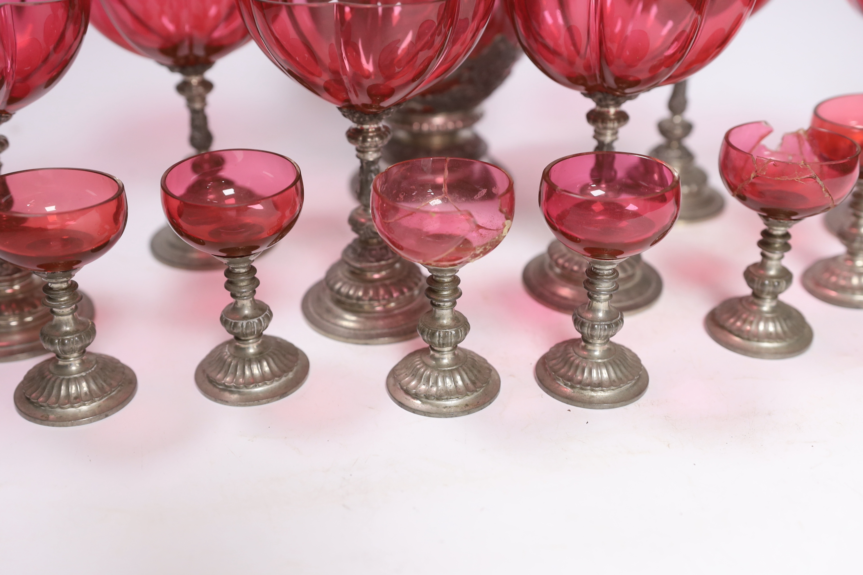 A Bohemian style pewter mounted cranberry glass ewer and twelve glasses, possibly Romanian, 33cm high